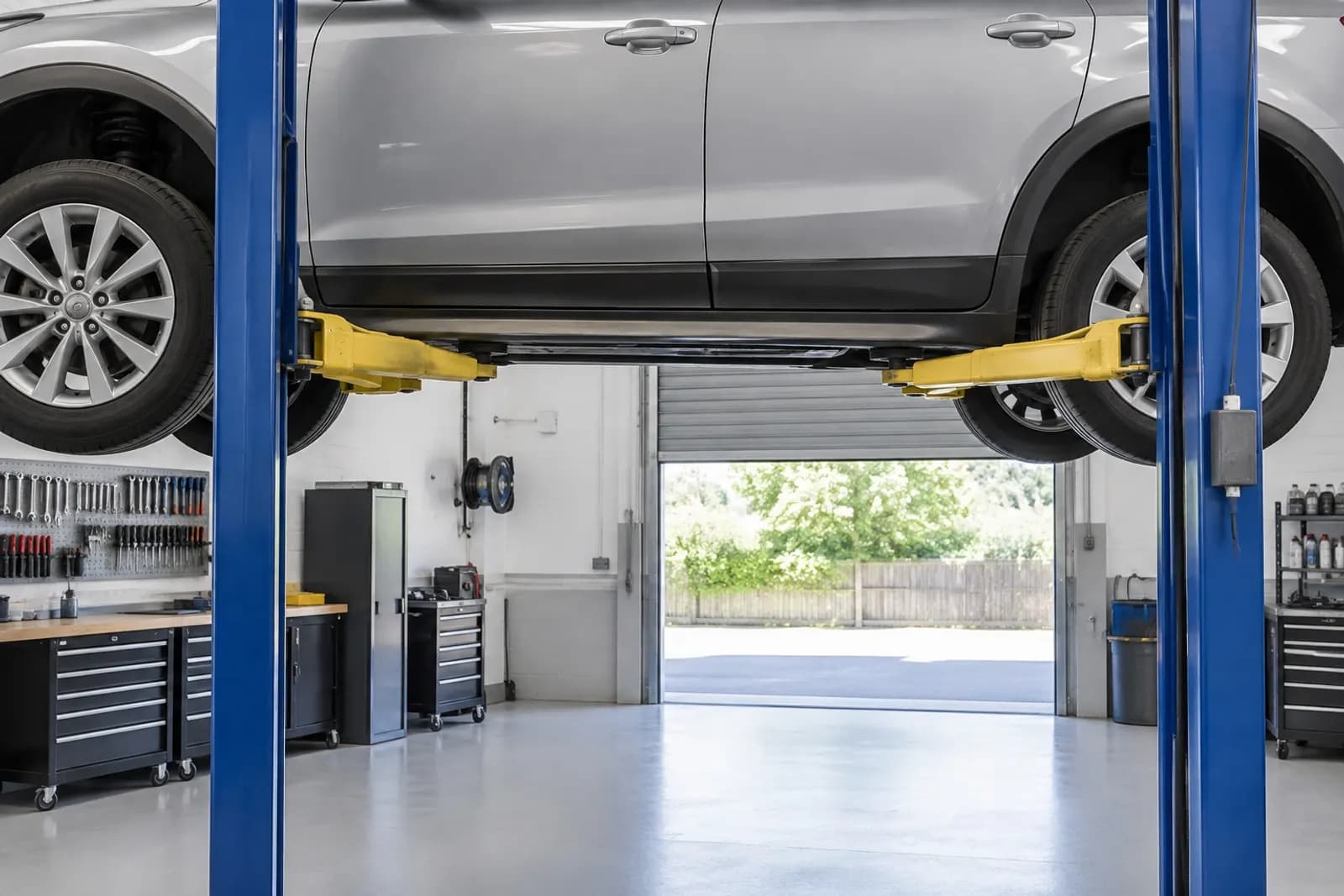 A bright, tidy garage workshop with a car raised on a lift